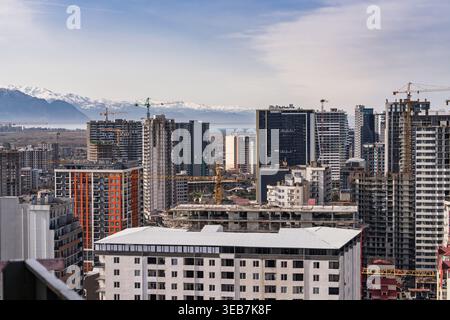 Batumi, georgia, 21 aprile 2026: Skyline della città di batumi che mostra numerosi edifici moderni in costruzione con gru, sullo sfondo di una calotta da neve Foto Stock