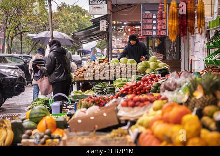 Batumi, georgia 21 aprile 2026: Venditore ambulante in piedi al suo banco, che offre una vasta gamma di frutta e verdura fresca ai clienti su un pipipistrello piovoso Foto Stock