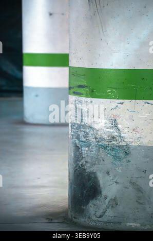 Vista dei pilastri in cemento con strisce verdi e segni di usura in un garage sotterraneo. Foto Stock