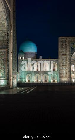 Vista della Madrasa Tilla-Kari illuminata con la sua cupola turchese e intricate piastrelle a mosaico di notte a Samarcanda, regione di Samarcanda, Uzbekistan. Foto Stock