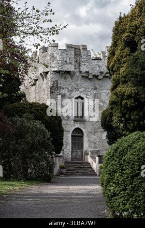 Una tradizionale casa a torre medievale in pietra circondata da lussureggianti alberi verdi. Foto Stock