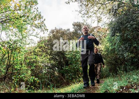 Persone che camminano attraverso il sentiero della foresta verde Foto Stock