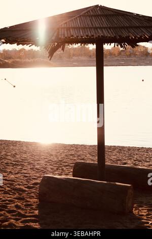 Calmo mare con ombrello solitario in una calda luce dorata Foto Stock
