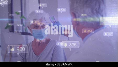Misurazione di un documento mascherato con guanti blu utilizzando una pistola a infrarossi su un paziente mascherato in clinica con icone sociali Foto Stock