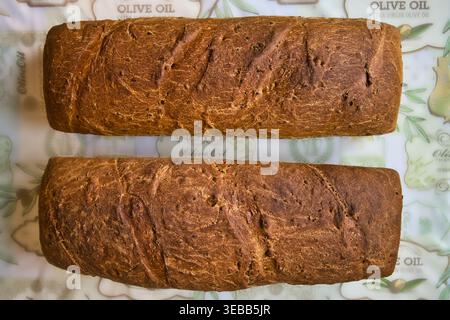 Due pani fatti in casa di farro integrale e pane di segale su tela a motivi di olio d'oliva. Foto Stock