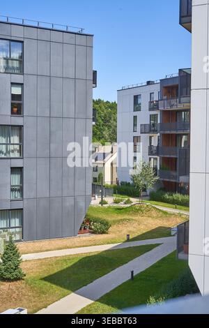 Edifici residenziali moderni con architettura contemporanea caratterizzati da facciate a pannelli grigi e grandi finestre, che circondano un paesaggio progettato Foto Stock