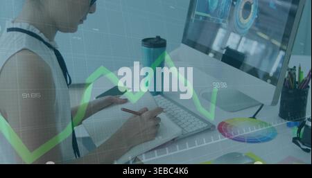Scrittrice alla scrivania con una parte superiore bianca senza maniche con nastro, osservando il monitor in un notebook con matita Foto Stock