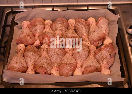 Cosce di pollo crude condite sul vassoio pronte per la tostatura Foto Stock