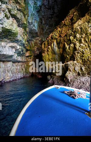 Viaggio in barca in una misteriosa grotta marina. L'acqua blu profonda incontra antiche e aspre pareti rocciose. Famosa grotta blu del Montenegro Foto Stock