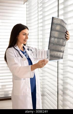 Medico donna in possesso di una scansione radiografica, che analizza la pellicola radiologica Foto Stock
