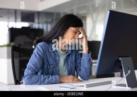 La donna tocca la fronte, si sente frustrata, sopraffatta o stressata Foto Stock