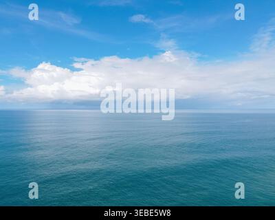 Vista aerea del vasto oceano blu con onde dolci sotto un cielo luminoso con nuvole bianche Tanjungsari, regione speciale di Yogyakarta, Indonesia. Foto Stock