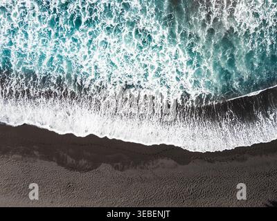 Vista aerea delle onde oceaniche che si infrangono sulla spiaggia di sabbia nera Foto Stock