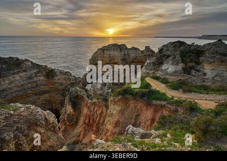 Tramonto sulla costa rocciosa dell'Algarve in Portogallo, con vista sull'Oceano Atlantico, scogliere aspre e suggestivo paesaggio costiero. Foto Stock