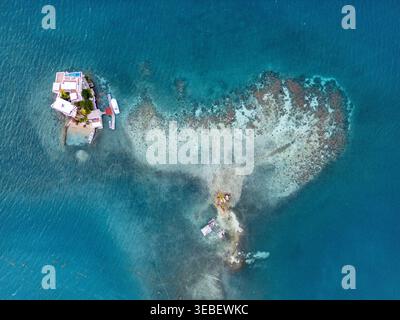 Vista aerea di una villa di lusso su una piccola isola privata accanto a una barriera corallina a forma di cuore in acque cristalline e turchesi Guanaja, Bay Islands Depar Foto Stock