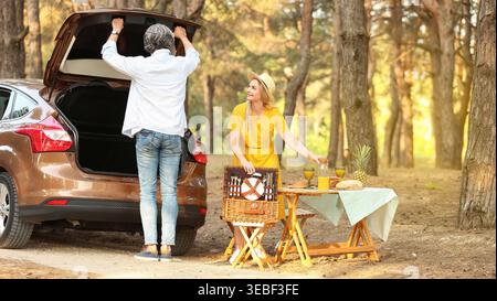 Coppia matura felice impostazione tabella per pic-nic in foresta Foto Stock