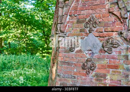 Vista ravvicinata di una struttura architettonica in mattoni rossi invecchiati con decorazioni in pietra disposte in un motivo a diamante simmetrico. Quattro Foto Stock