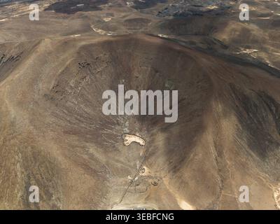 Vista aerea del profondo cratere vulcanico con i suoi aridi pendii rossastri e il terreno accidentato nel paesaggio vulcanico di Lanzarote, Canarias, Spagna. Foto Stock