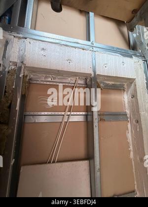 Installazione di una batteria antincendio all'interno di una parete incompiuta con cablaggio e cartongesso Foto Stock