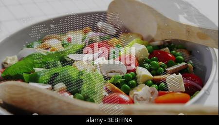 Esposizione di insalate in ceramica bianca sedute sul tavolo della cucina, con cucchiai di legno e rivestimento a mezzitoni Foto Stock