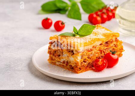 Lasagne tradizionali con salsa bolognese condite con foglie di basilico servite su un piatto bianco Foto Stock
