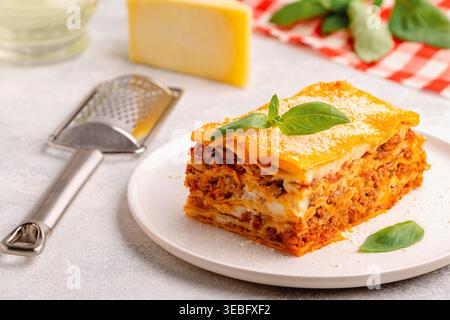 Lasagne tradizionali con salsa bolognese condite con foglie di basilico servite su un piatto bianco Foto Stock