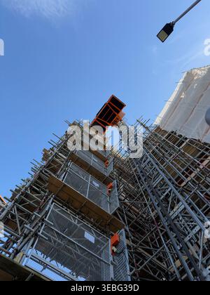 Alto ponteggio di costruzione con ascensore contro il cielo limpido Foto Stock