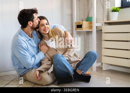 Coppia felice e variegata che condivide un momento di gioia a casa, abbracciando e sorridendo insieme Foto Stock