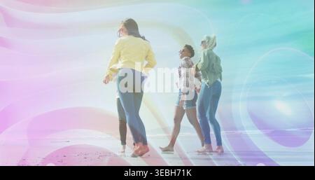 Camminare quattro donne lungo il litorale sabbioso indossando giacche jeans pantaloncini a piedi nudi che mostrano turbolenza pastello Foto Stock