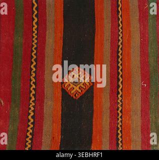 Tradizionale tappeto kilim intrecciato che mostra vivaci motivi a righe e un motivo geometrico centrale, un'antica arte che crea texture e manualità culturali Foto Stock