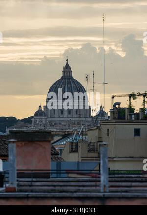 Roma, Italia - 06 giugno 2024: Veduta della cupola della Basilica di San Pietro che si innalza sopra i tetti urbani e le antenne televisive sotto un cielo nuvoloso al tramonto. Foto Stock
