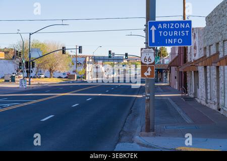 Storica Route 66 e cartelli informativi turistici dell'Arizona su un palo lungo una strada statale deserta sotto un cielo sereno a Holbrook, Arizona Foto Stock