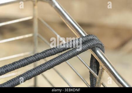 Vista ravvicinata che mostra la cinghia elastica nera del cavo elastico avvolta saldamente su un cestello metallico per una tensione sicura e affidabile che tiene saldamente l'attrezzatura Foto Stock