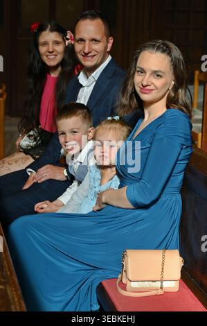 Famiglia con due bambini seduti nella chiesa durante la cerimonia nuziale Foto Stock