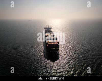Vista aerea di una grande nave portacontainer in mare aperto al tramonto Foto Stock