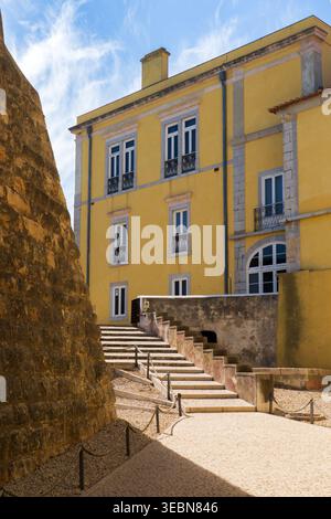 Lisbona, Portogallo - 7 maggio 2022: Vista di un radioso edificio storico giallo, le sue finestre bianche e croccanti contrastano con le aspre pareti di pietra e le luci del sole Foto Stock