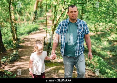 Padre e figlia camminano insieme su un sentiero boschivo Foto Stock