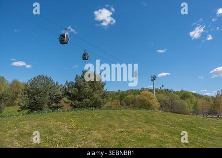 Germania Berlino 26 aprile 2026. Le funivie scivolano sulle verdi colline sotto i cieli blu. Alberi e fiori selvatici punteggiano il paesaggio. Tranquilla giornata estiva perfec Foto Stock