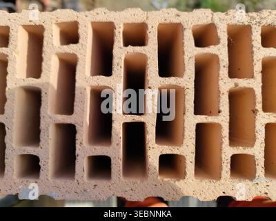 Mattoni cavi in argilla con cavità rettangolari multiple mostrati in primo piano nel cantiere. Materiali da costruzione, muratura, costruzione, architettura, Foto Stock