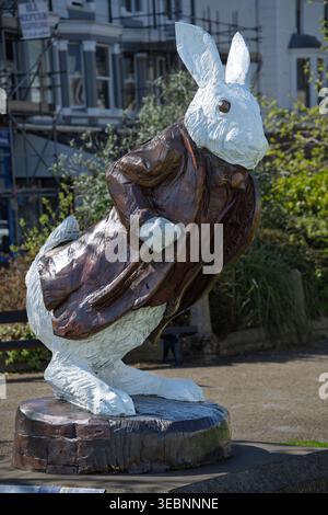 A Llandudno, nel Galles del Nord, un'affascinante statua di coniglio bianco si erge orgogliosamente, catturando lo spirito stravagante di Alice nel Paese delle meraviglie. I visitatori lo ammirano Foto Stock