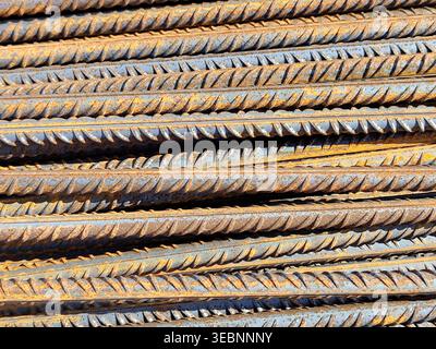 Barre di rinforzo in acciaio arrugginito impilate in file parallele con superficie ruvida e segni di corrosione nel cantiere. Materiali da costruzione, Ind. Metallo Foto Stock