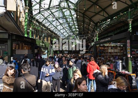 Folle di persone che camminano attraverso un affollato mercato alimentare del Borough al coperto. Londra, Regno Unito, 29 marzo 2024 Foto Stock