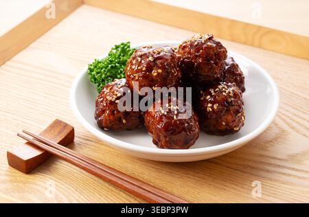Deliziose polpette dolci e acide giapponesi (niku-dango) con semi di sesamo e bacchette Foto Stock