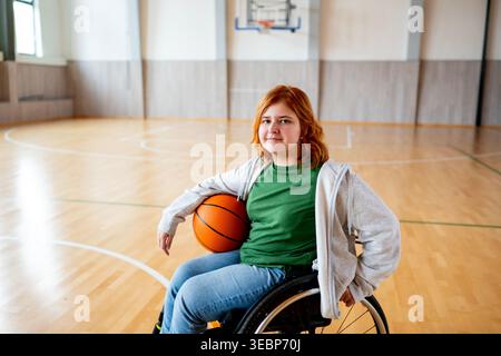 Ritratto di una giovane donna in sedia a rotelle che gioca a basket. Foto Stock