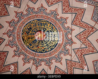 Squisita vista interna di una cupola della moschea ottomana caratterizzata da un'intricata calligrafia araba dorata e colorate fantasie geometriche a stella a Istanbul Foto Stock