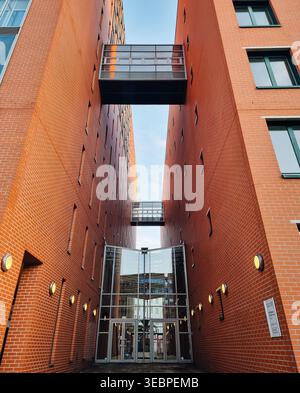 Moderni edifici per uffici in mattoni con connettori Skybridge in vetro. Ripresa simmetrica ad angolo basso di edifici contemporanei in mattoni rossi con passerelle in vetro Foto Stock