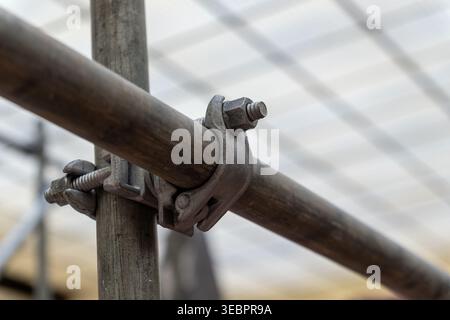 Primo piano di un morsetto per ponteggi in metallo per impieghi pesanti che simboleggia i collegamenti e la struttura e fornisce ampio spazio di copia. Foto Stock
