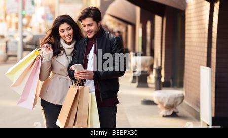 Giovani coppie che amano fare shopping insieme su una strada della città alla luce del pomeriggio Foto Stock
