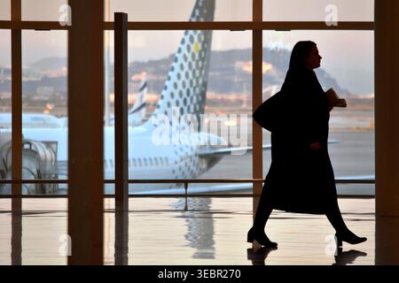 Barcellona, Spagna - 4 gennaio 2020: Silhouette di una donna d'affari che cammina attraverso il terminal dell'aeroporto con l'aereo fuori dalla finestra Foto Stock
