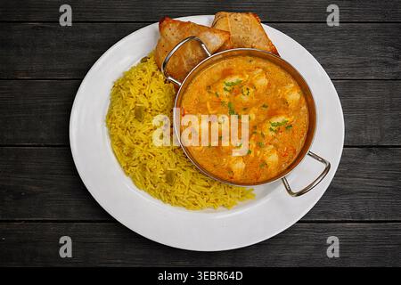Curry indiano di korma di pollo in un piatto con riso pilau ***fotografia originale del contributore, modificata utilizzando strumenti ai ** Foto Stock